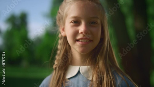 Blonde girl posing alone with pigtail closeup. Gentle kid look camera in park photo