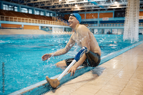 Photography Athlete with prosthetic leg has fun while splashing water by the edge of swimming pool