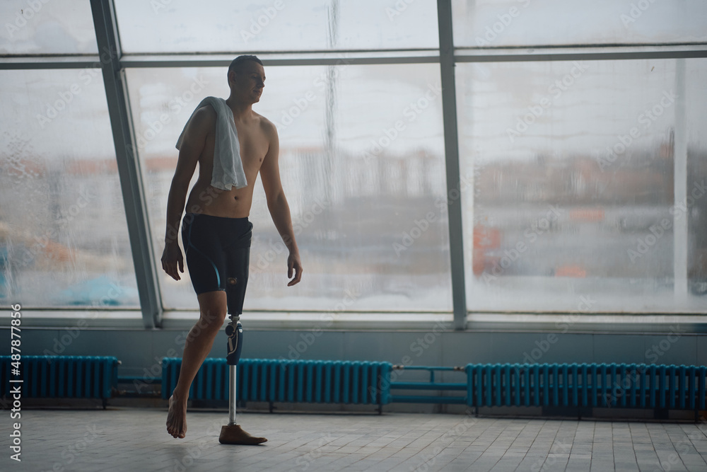 Full length of male swimmer with artificial leg at indoors sports facility. Full length of male swimmer with artificial leg at indoors sports facility.