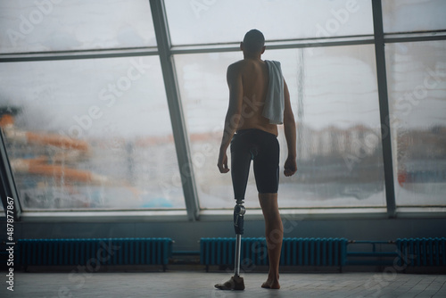 Rear view of swimmer with artificial leg looking through the window.