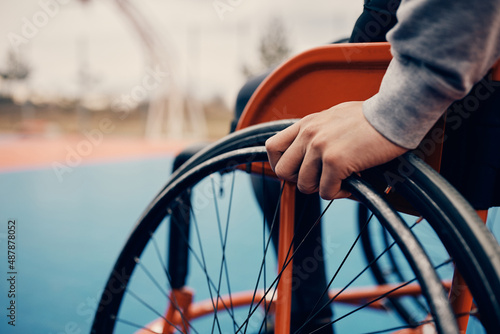 Photo Close-up of man in wheelchair on an outdoor basketball court.