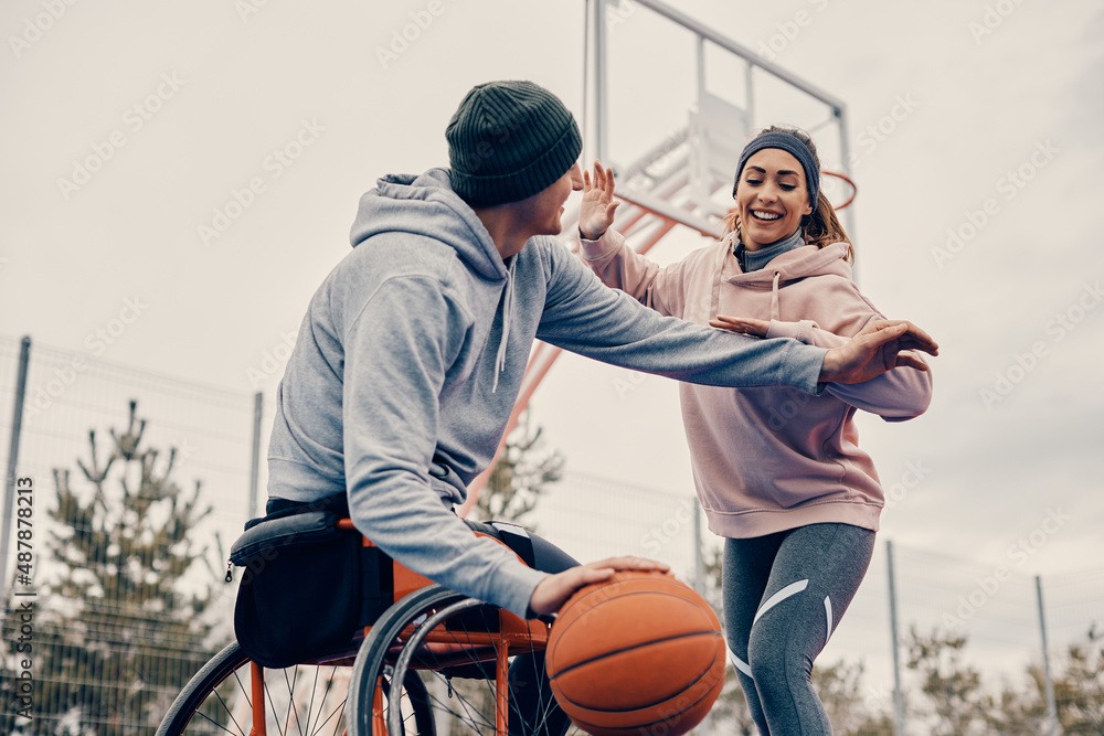 Happy woman has fun while playing basketball with her friend in wheelchair. Happy woman has fun while playing basketball with her friend in wheelchair.