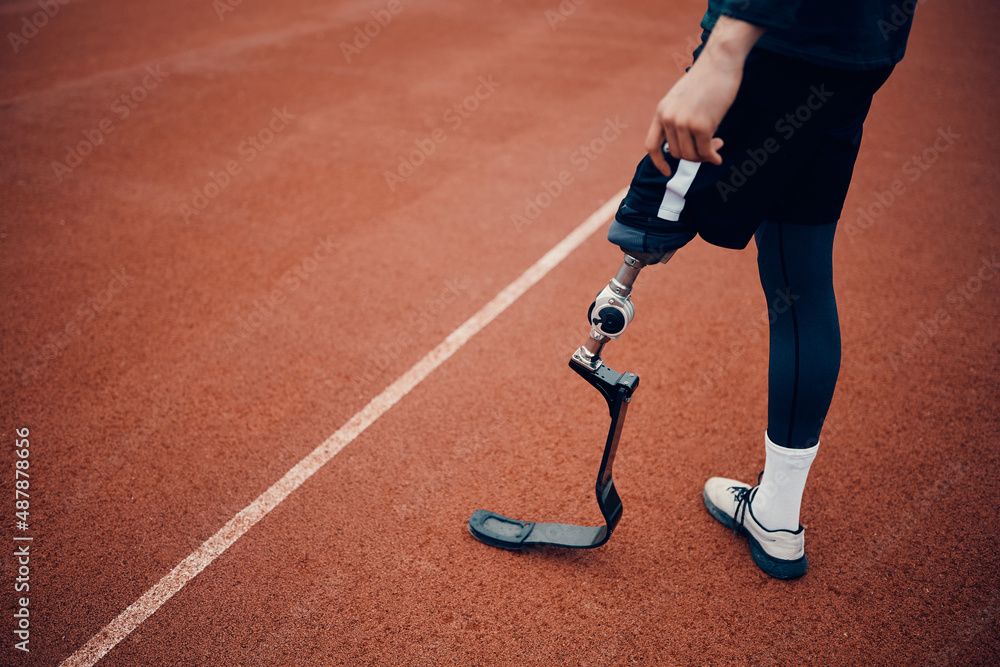 Unrecognizable athletic man with artificial leg on running track at the stadium. Unrecognizable athletic man with artificial leg on running track at the stadium.