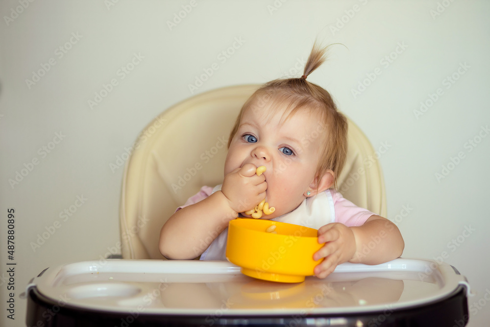 Little girl eats delicious pasta at the table in the kitchen Little girl eats delicious pasta at the table in the kitchen