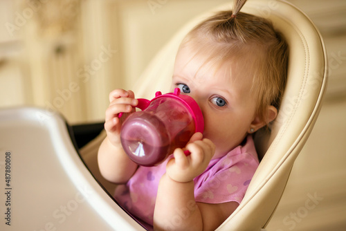 little girl drinks compote from a sippy cup