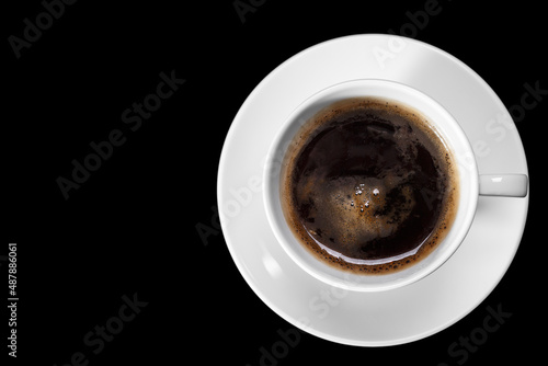 A cup of coffee on a white saucer on a black background. Flat layout.