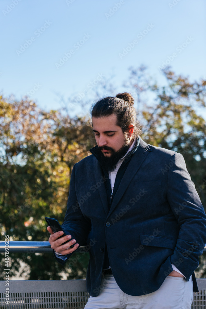 Young business man looking mobile next to the offices Young business man looking mobile next to the offices