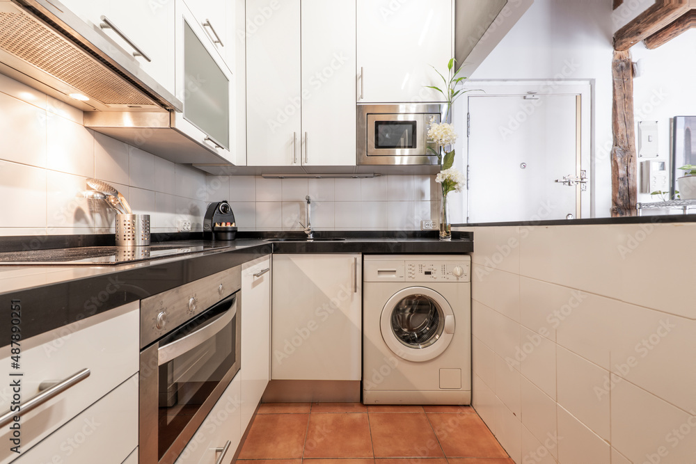 Fototapeta premium Kitchen with white cabinets and stainless steel appliances with clay terrazzo flooring in a vacation rental apartment
