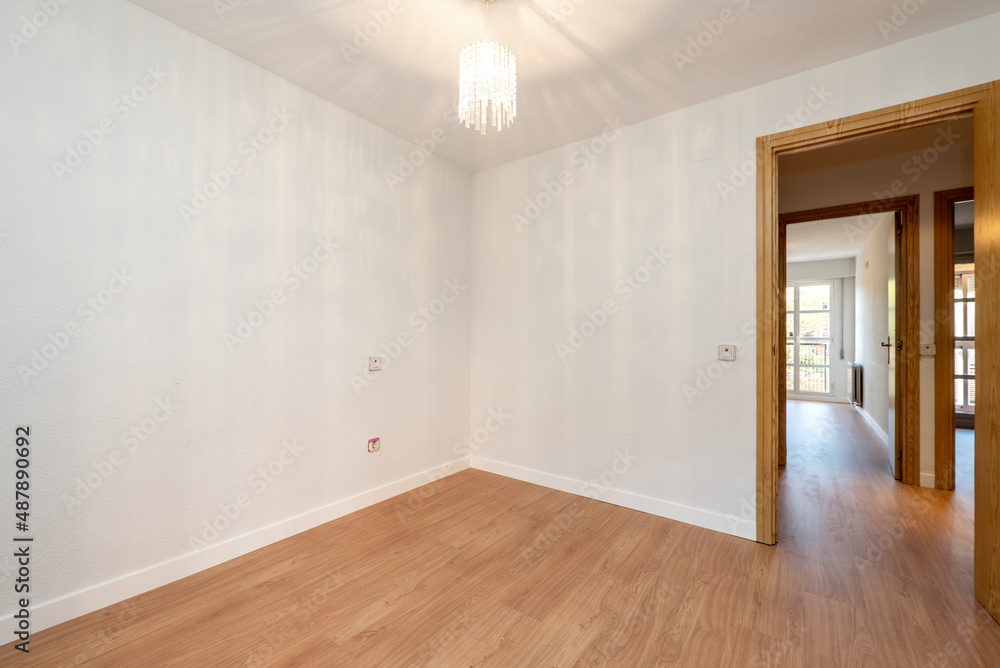 Empty room with wooden floors, oak woodwork on the doors and glass lamp on the ceiling Empty room with wooden floors, oak woodwork on the doors and glass lamp on the ceiling
