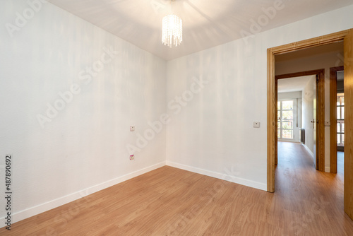 Empty room with wooden floors  oak woodwork on the doors and glass lamp on the ceiling