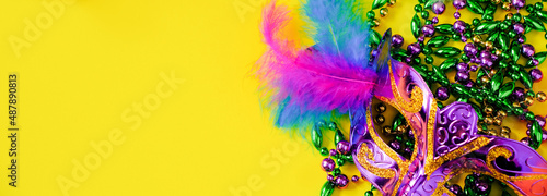 Carnival mask with feathers on yellow background. Multicolored beads Mardi Gras or Fat Tuesday symbol.