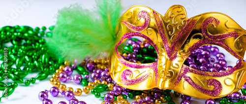 Golden carnival mask and colorful beads close-up. Mardi Gras or Fat Tuesday symbol.