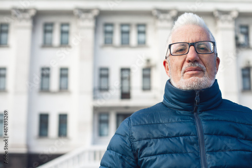 Active retirement concept. Portrait of handsome silver haired mature man watching signtseeing attractions in center of old European capital city. Nice winter day. Modern haircut, beard. Outdoor shot photo