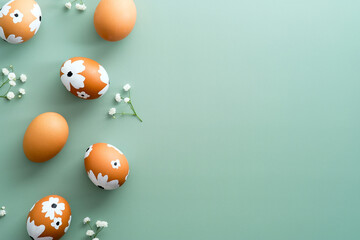 Happy Easter card design. Easter eggs decorated with flowers on pastel green background. Flat lay, top view.