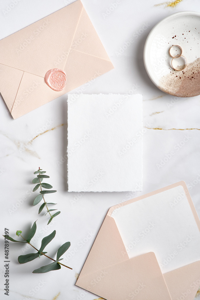 Wedding invitation mockup, pastel pink envelopes, golden rings, eucalyptus leaves on marble table. Elegant wedding stationery set. Flat lay, top view. Wedding invitation mockup, pastel pink envelopes, golden rings, eucalyptus leaves on marble table. Elegant wedding stationery set. Flat lay, top view.