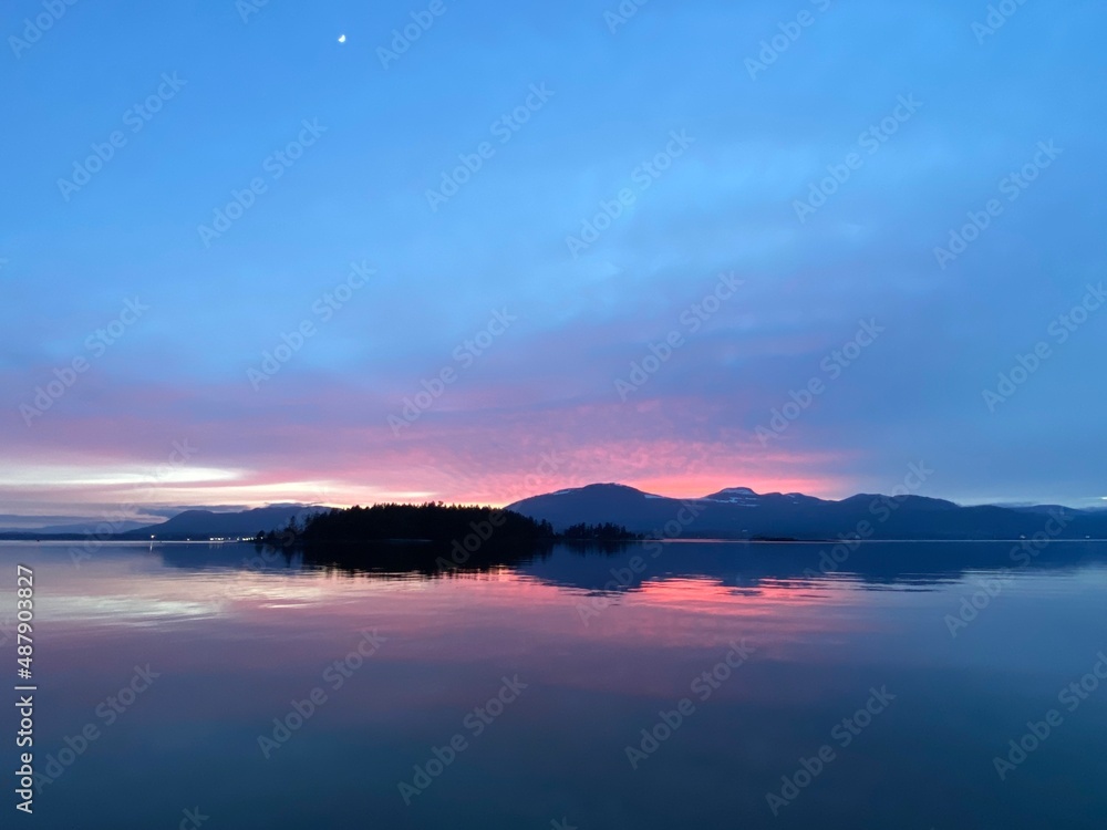 Pink sunset over mountains with reflection on water