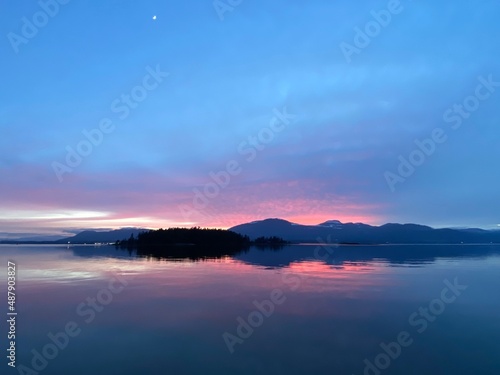 Pink sunset over mountains with reflection on water