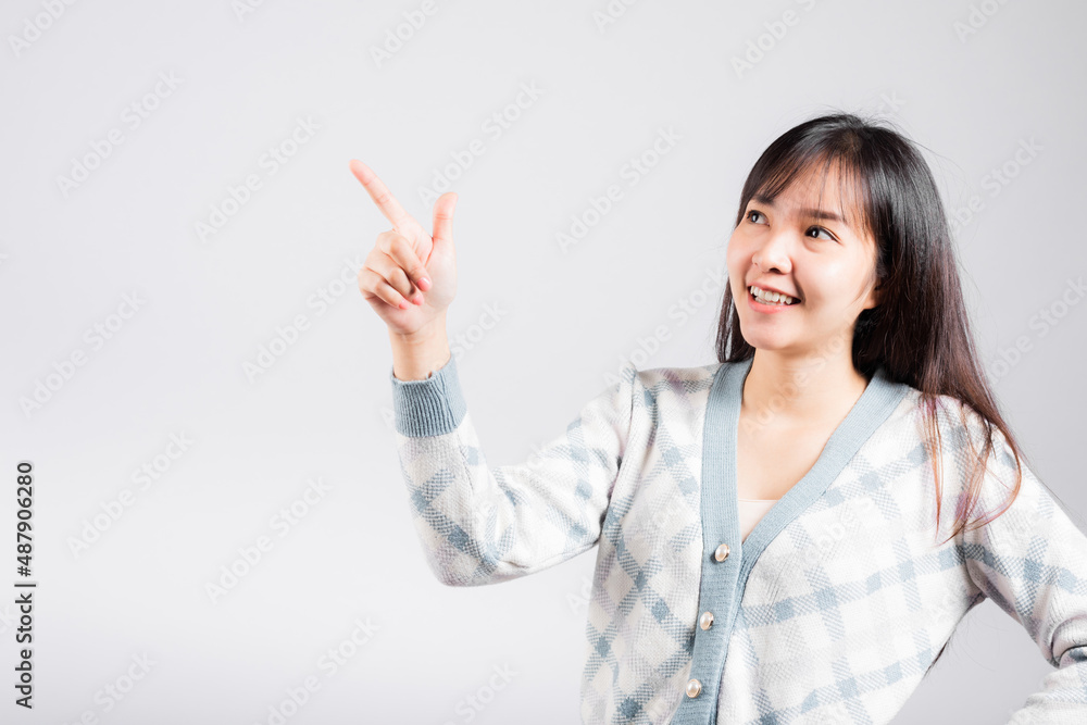 Smiling happy woman pointing finger out space, Portrait Asian beautiful young female point into empty looking to side away, studio shot isolated on white background with copy space Smiling happy woman pointing finger out space, Portrait Asian beautiful young female point into empty looking to side away, studio shot isolated on white background with copy space