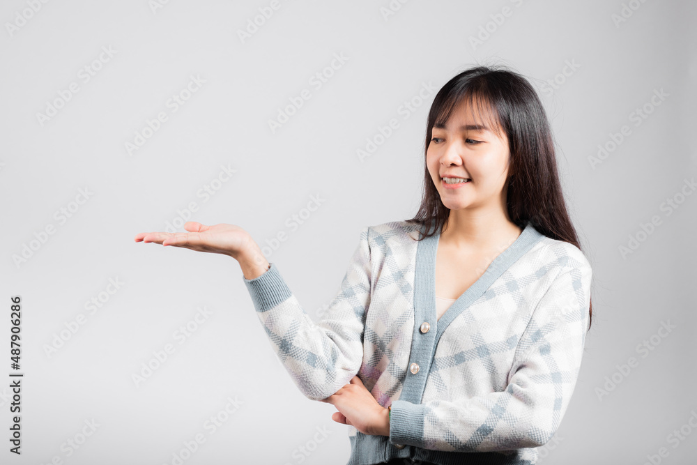 Smiling happy woman presenting product holding something on palm away side, Portrait Asian beautiful young female show hand demonstrate gesture studio shot isolated on white background with copy space Smiling happy woman presenting product holding something on palm away side, Portrait Asian beautiful young female show hand demonstrate gesture studio shot isolated on white background with copy space