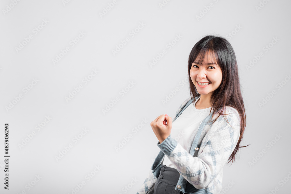 Smiling happy woman makes raised fists up celebrating her winning success gesture, Happy Asian beautiful young female excited say yes, studio shot isolated on white background with copy space Smiling happy woman makes raised fists up celebrating her winning success gesture, Happy Asian beautiful young female excited say yes, studio shot isolated on white background with copy space