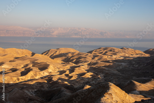 Beautiful landscape of Israeli Judean Desert mountains, with sunrise over the dry riverbed of Nahal Dragot Wadi, popular hiking trail winding between rugged rocky cliffs towards the Dead Sea. High photo