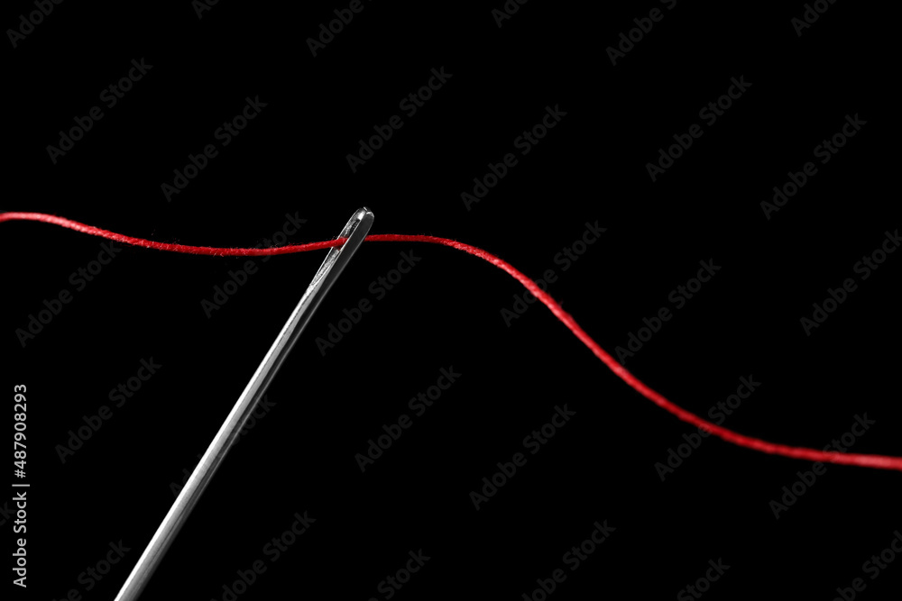 Sewing needle with red thread on black background Stock Photo