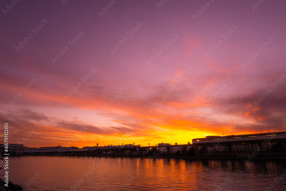 夕暮れ時にオレンジ色に照らされる雲と運河の風景