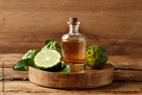 Glass bottle of bergamot essential oil on wooden table photo