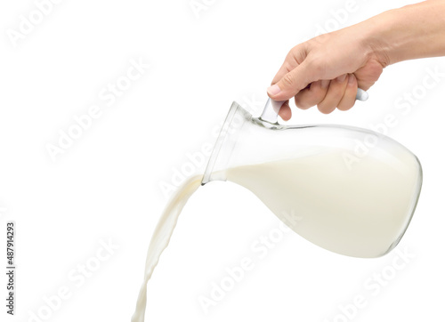 Pouring fresh milk from the glass pitcher isolated on white background.