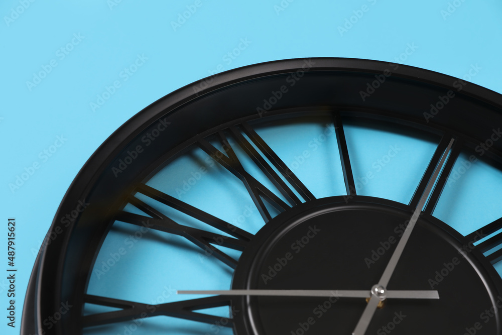 Stylish analog clock on light blue background, closeup