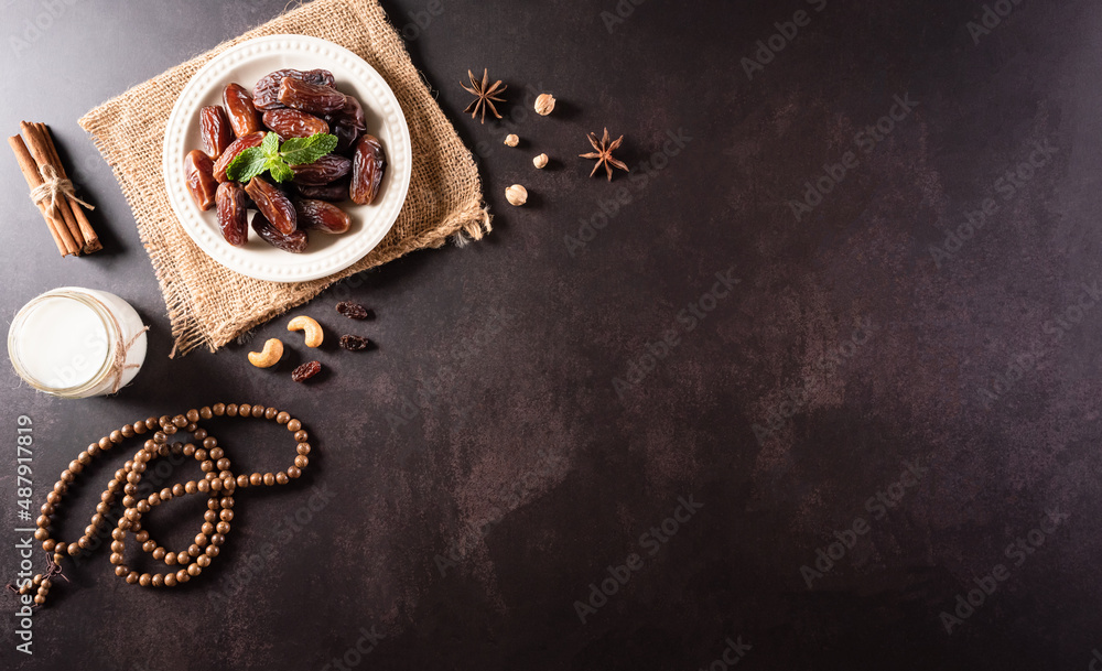 Ramadan Kareem background concept, Rosary bead with dates fruit and milk on dark stone background.