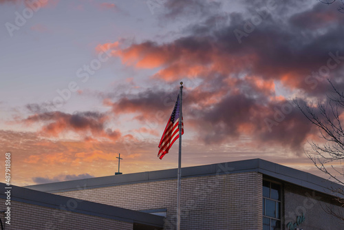 an American Flag on top of a gray building with red sky and powerful clouds in Douglasville Georgia USA photo