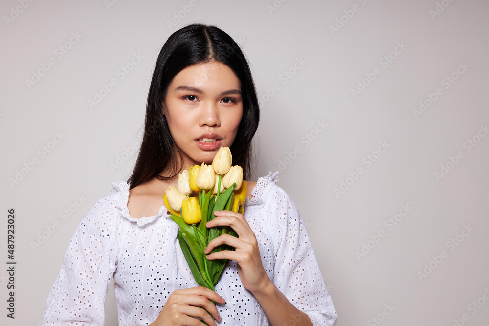 Charming young Asian woman romance bouquet of flowers near the face light background unaltered Charming young Asian woman romance bouquet of flowers near the face light background unaltered