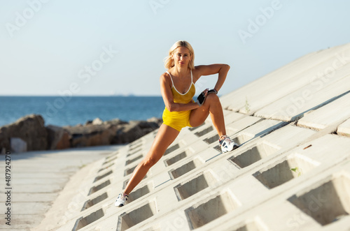 Athletic woman exercising from a concrete surface on the beach. Fitness, outdoor aerobics concept