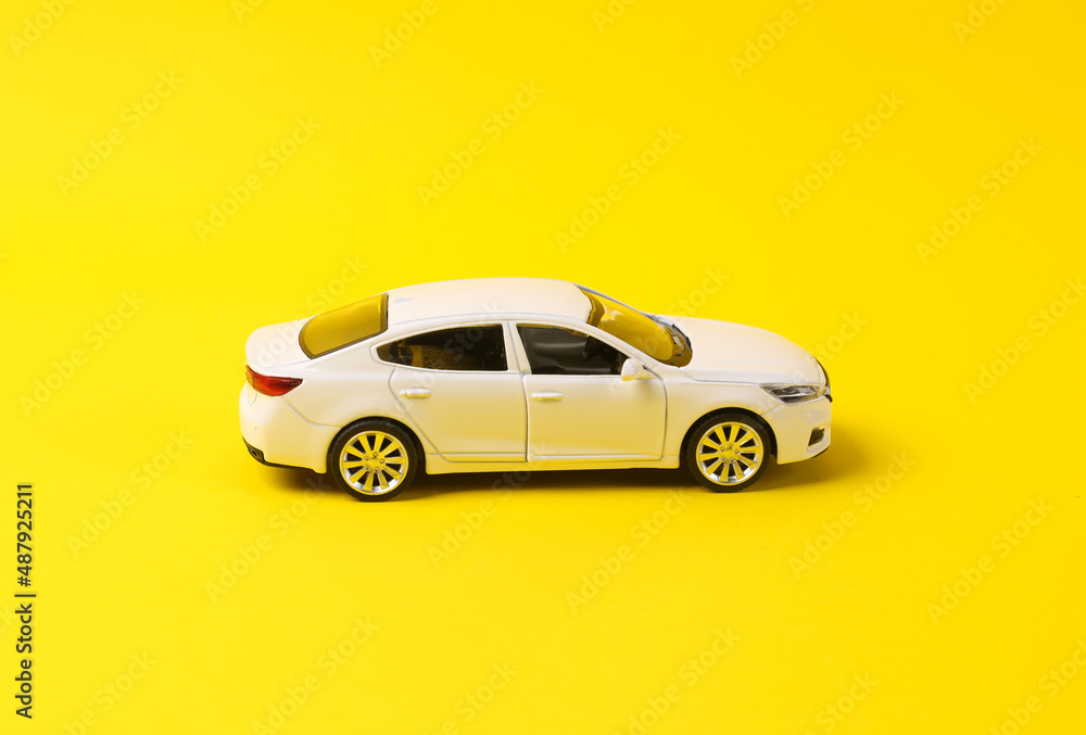 Mini model of white toy car on yellow background
