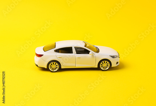 Mini model of white toy car on yellow background