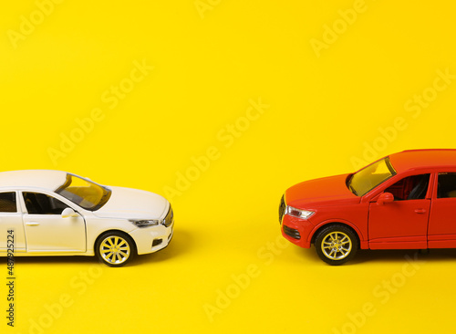 Two toy cars opposite each other on a yellow background