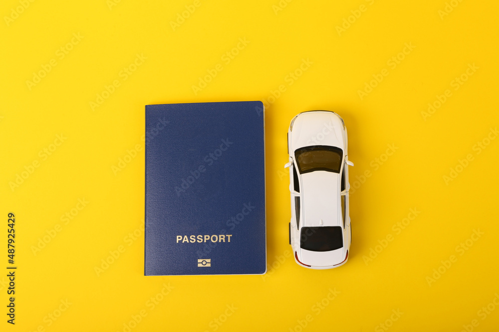 Toy car model with a passport on a yellow background. Travel concept Toy car model with a passport on a yellow background. Travel concept