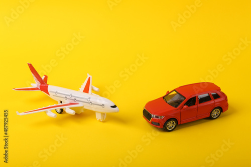 Toy car model with an airplane on a yellow background. Travel concept