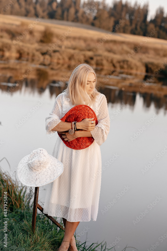 A cute girl with short blond hair in a long white dress with a hat in ...
