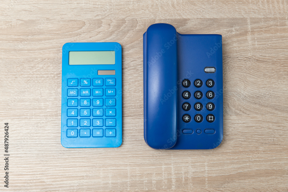 Office landline phone and calculator on wooden table Office landline phone and calculator on wooden table