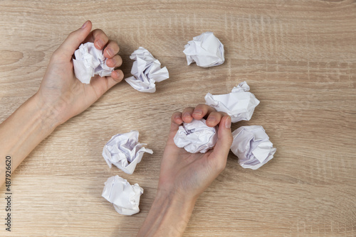 Hands holds crumpled balls of paper on wooden table