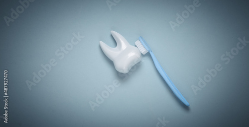 Fototapeta Naklejka Na Ścianę i Meble -  Toothbrush cleans toy plastic tooth on blue background. Dental care concept