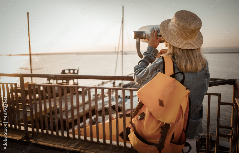 Pretty Woman tourist looks looks through city binoculars. Travel and tourism concept. Discover new places