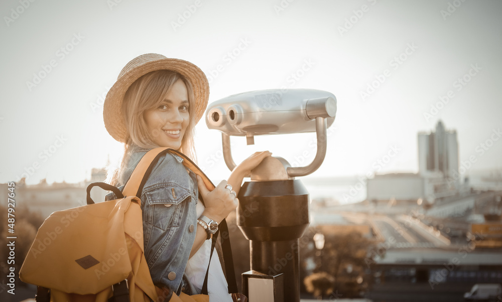 Pretty Woman tourist looks looks through city binoculars. Travel and tourism concept. Discover new places