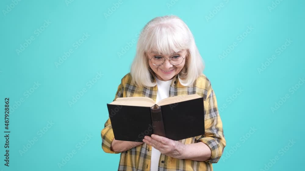 Smart granny free time read interesting book isolated cyan color background Smart granny free time read interesting book isolated cyan color background