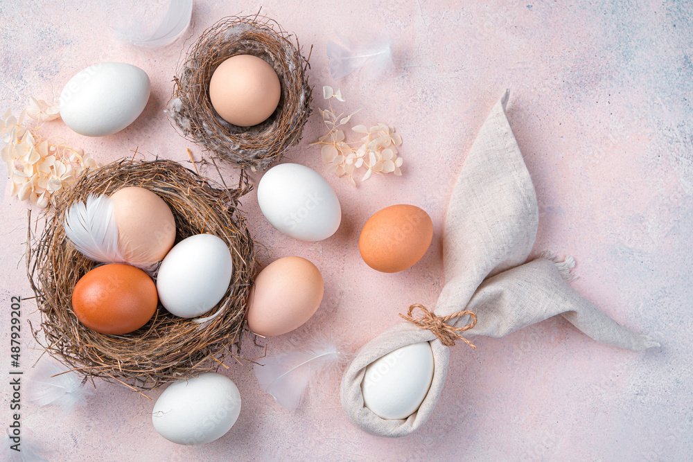 Happy Easter, festive background with natural eggs in the nest and an Easter bunny from a napkin on a light pink background. Happy Easter, festive background with natural eggs in the nest and an Easter bunny from a napkin on a light pink background.