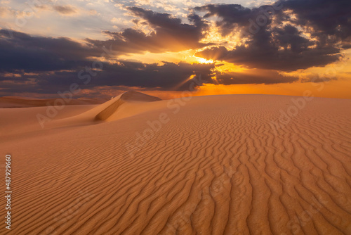 Sunset over the sand dunes in the desert. Arid landscape of the Sahara desert.