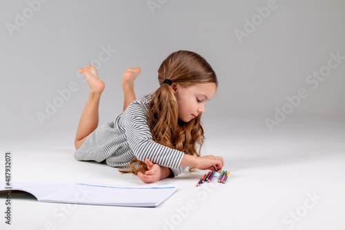 little girl in a striped dress draws in an album lying on the floor. child development. lifestyle