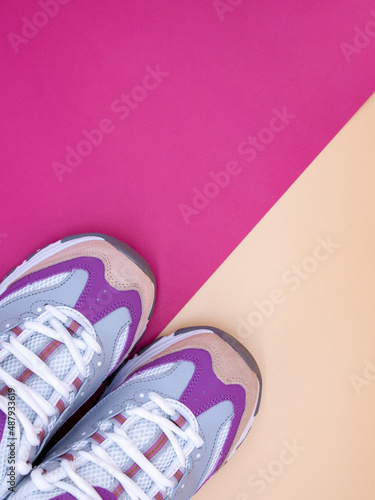 Pair of new stylish sneakers on a pastel orange and bright pink background, copy space